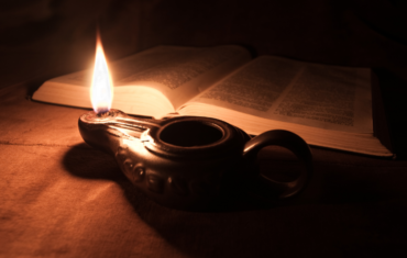 Antike Öllampe vor einer Bibel
